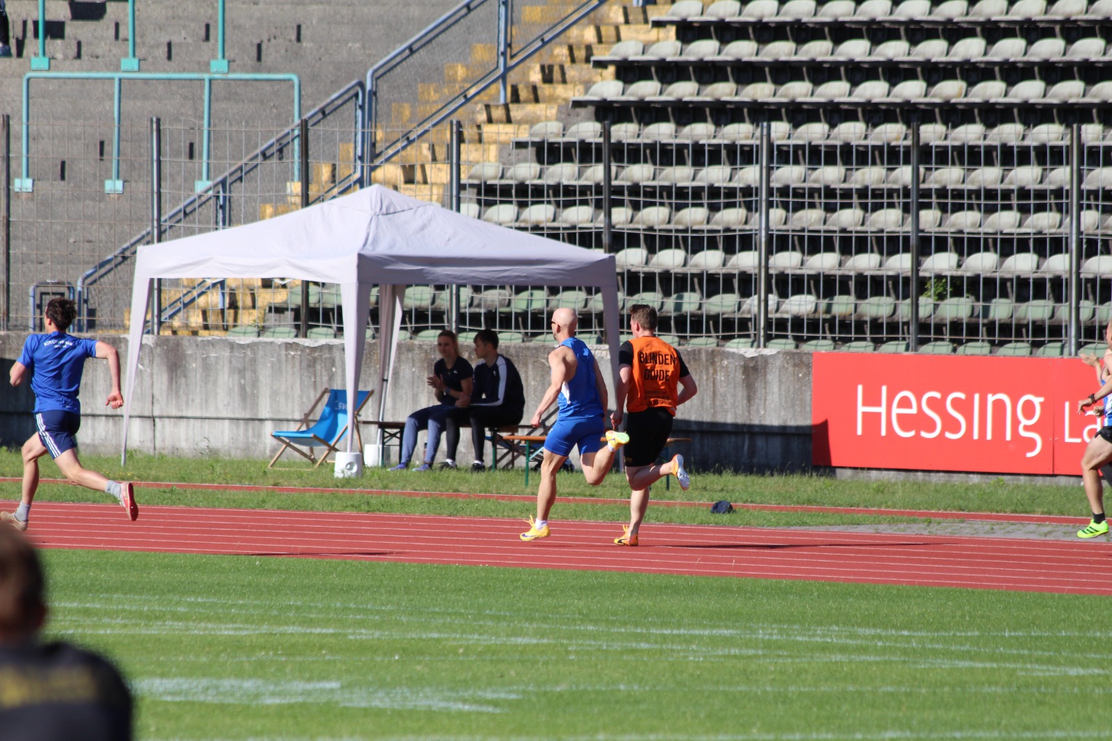 Stefan und Simon laufen nebeneinander auf der Geraden, im Hintergrund ein Hessing-Banner.